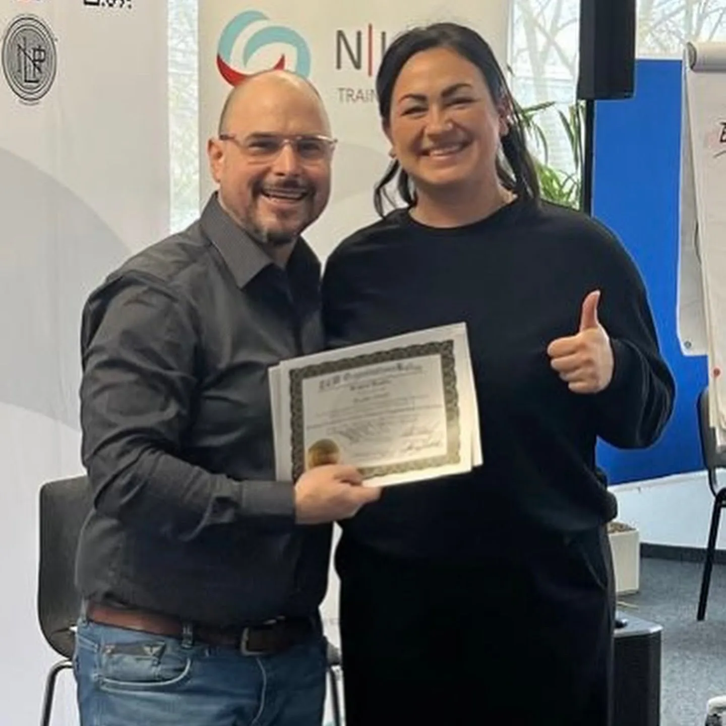 NLP Practitioner Ausbildung München – Thorsten Winkler bei Urkundenübergabe mit NLP Practitioner Absolventin